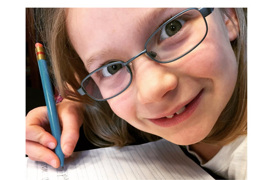 girl with glasses with pencil writing in notebook